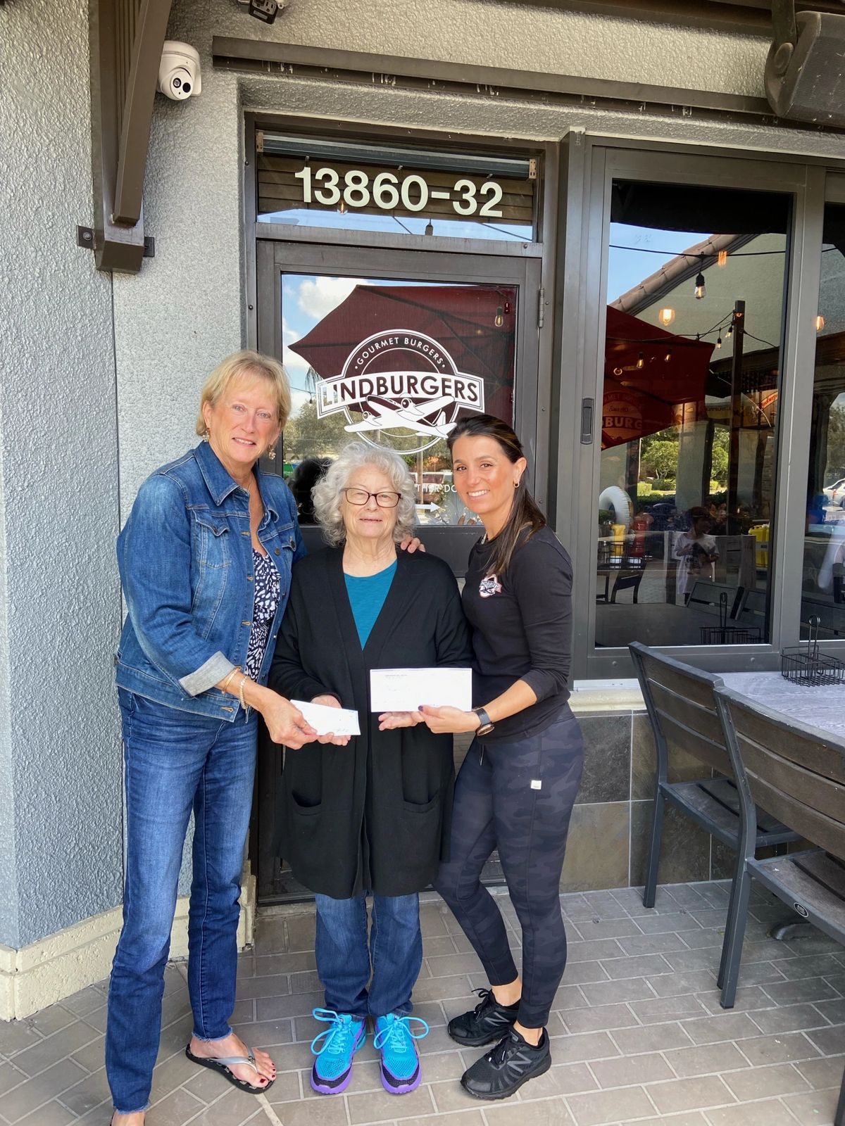 Connie Saxon, Becky Turner, and a Lindburgers bartender holding a large presentation check