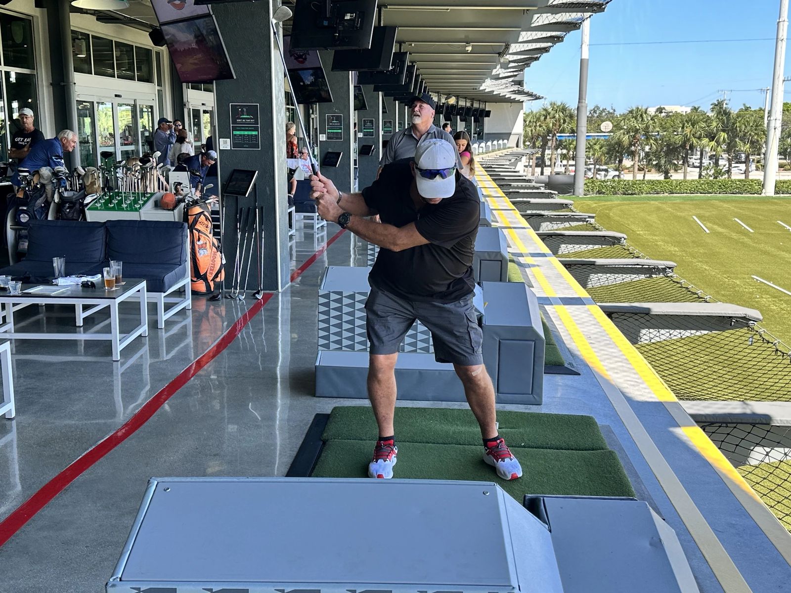 A supporter taking a swing in a hitting bay at Drive Shack